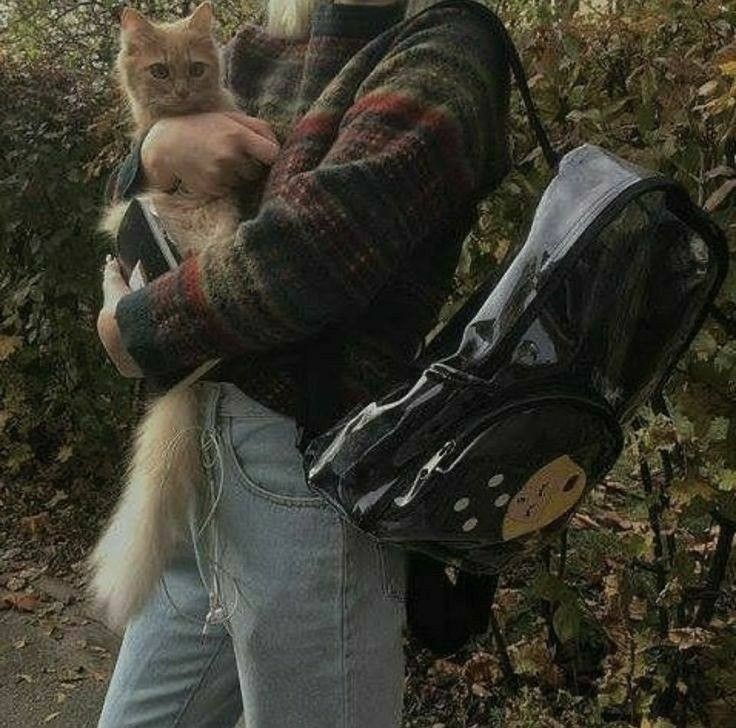 a person holding a cat in their arms while wearing a backpack and jeans with polka dots on them