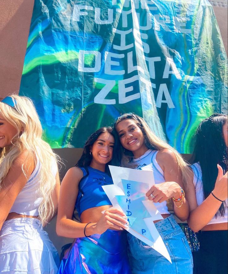 three beautiful young women standing next to each other in front of a blue and green banner