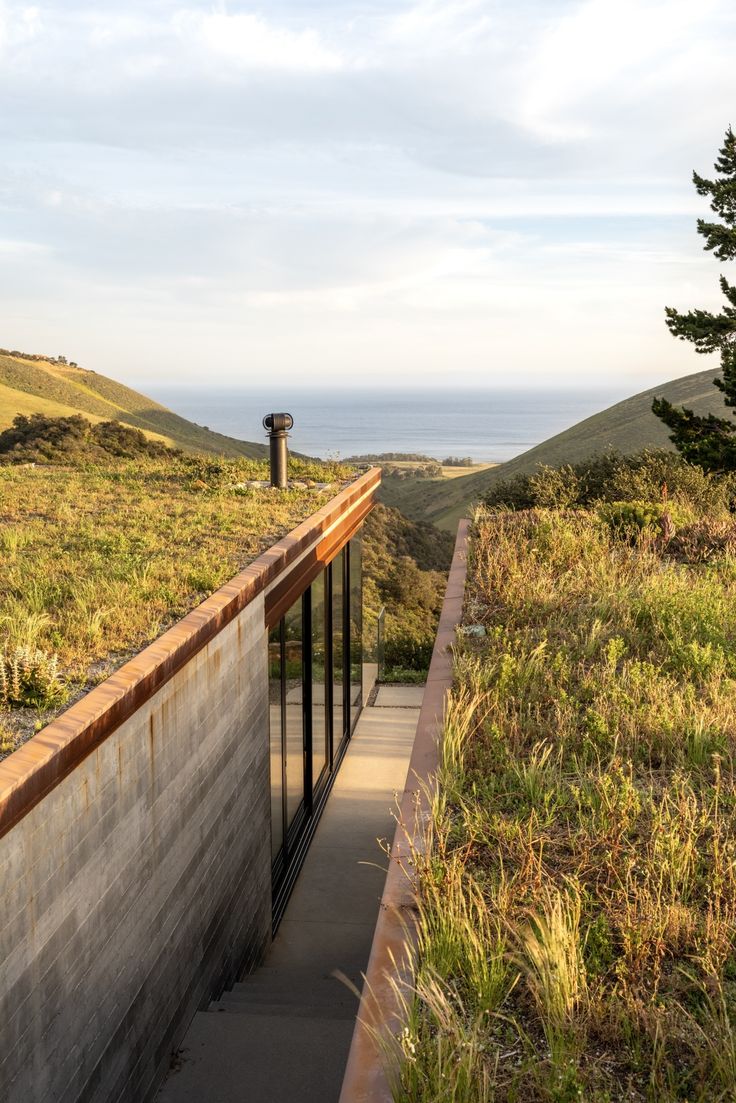 an empty walkway leading to the top of a hill with grass and trees on it