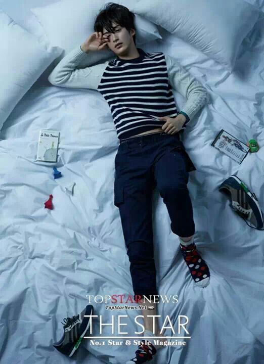 a young man laying on top of a bed next to pillows