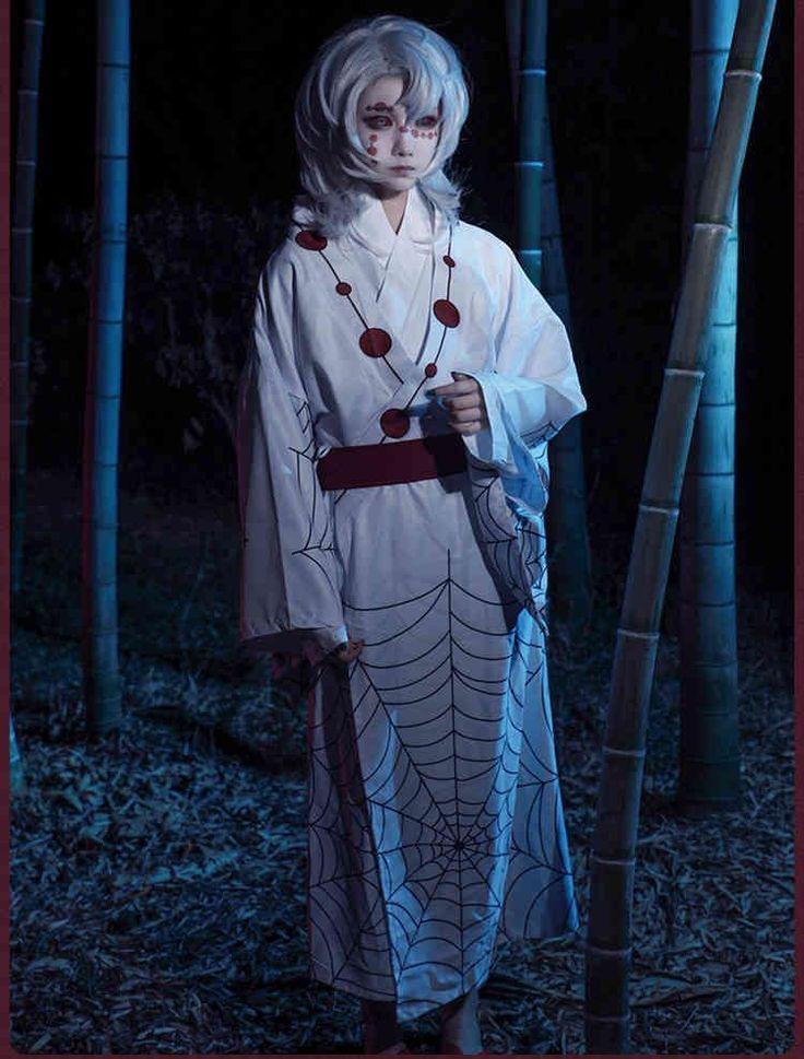 a woman dressed as a ghost standing in front of some bamboo trees with her hands on the ground