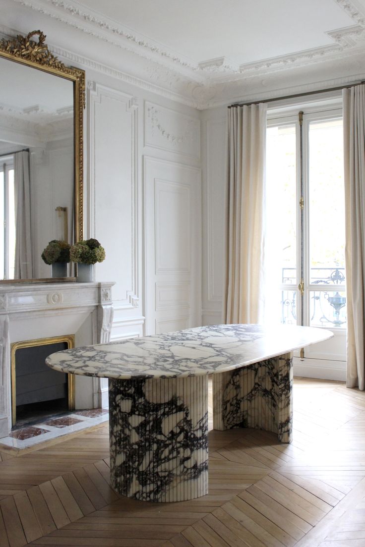 an elegant dining table in the middle of a living room with fireplace and large mirror