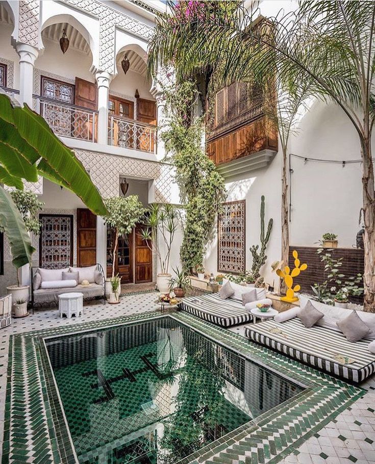 an indoor swimming pool surrounded by greenery and potted plants in the middle of a courtyard