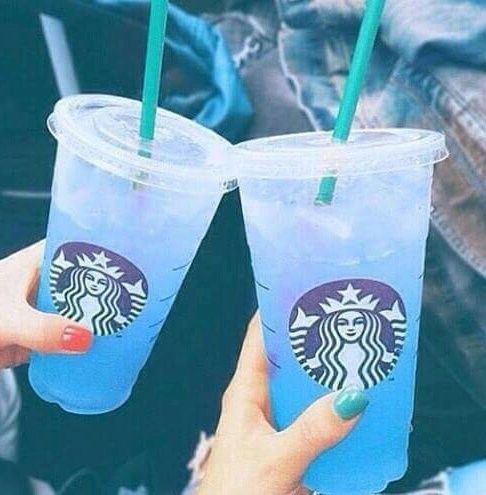 two people holding up starbucks cups with green straws