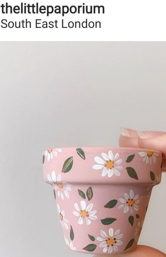 a person holding a pink flower pot with white flowers on it and the words little papooum south east london