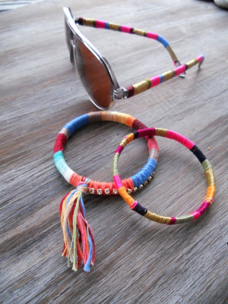 three bracelets with tassels are sitting on the floor next to a pair of sunglasses