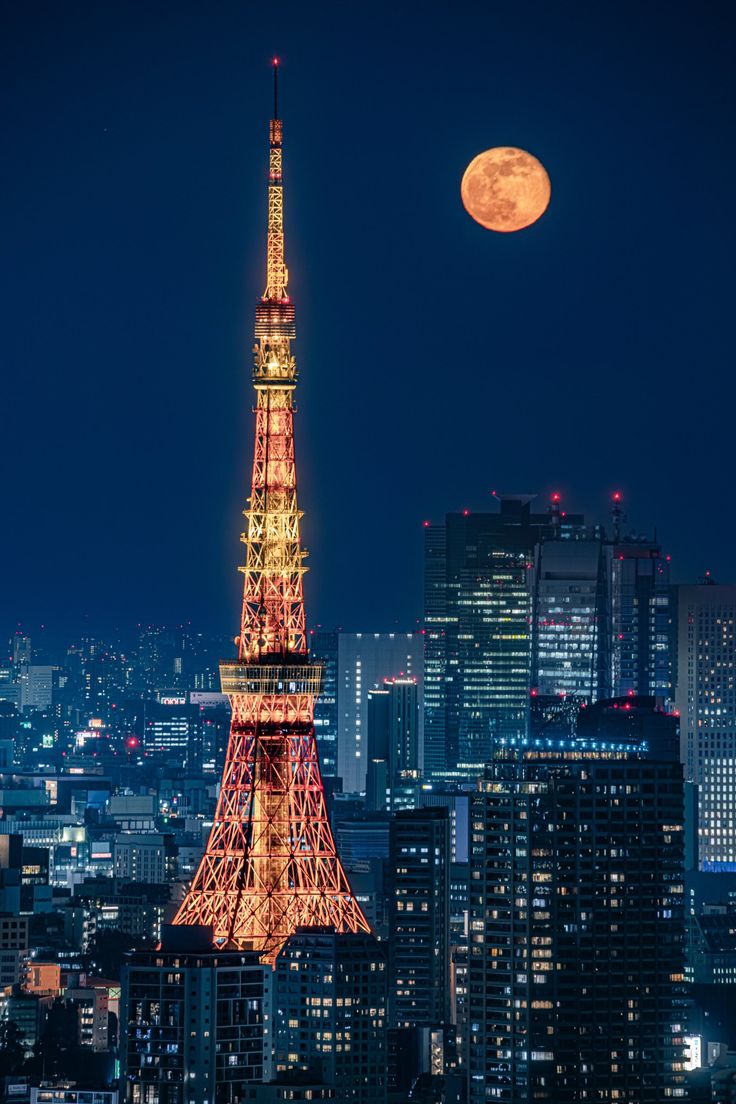 the eiffel tower lit up at night in paris, france with the full moon behind it