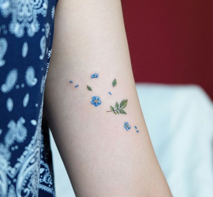 a woman's arm with small blue flowers on the left side of her arm