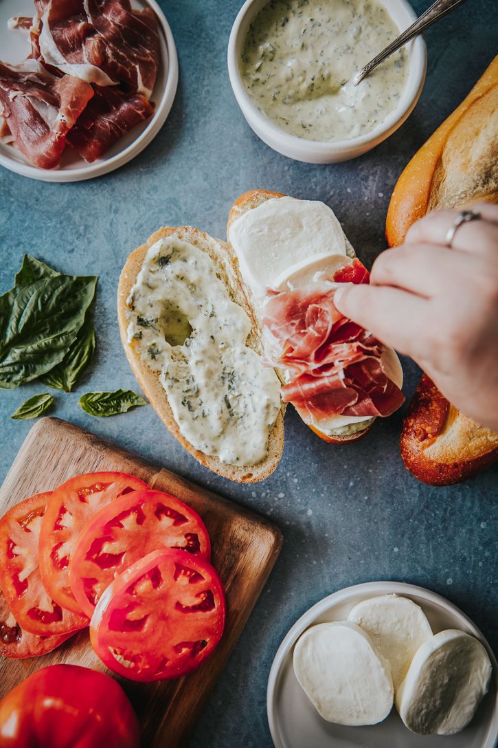 several different types of food sitting on a table next to bread, tomatoes and cheese