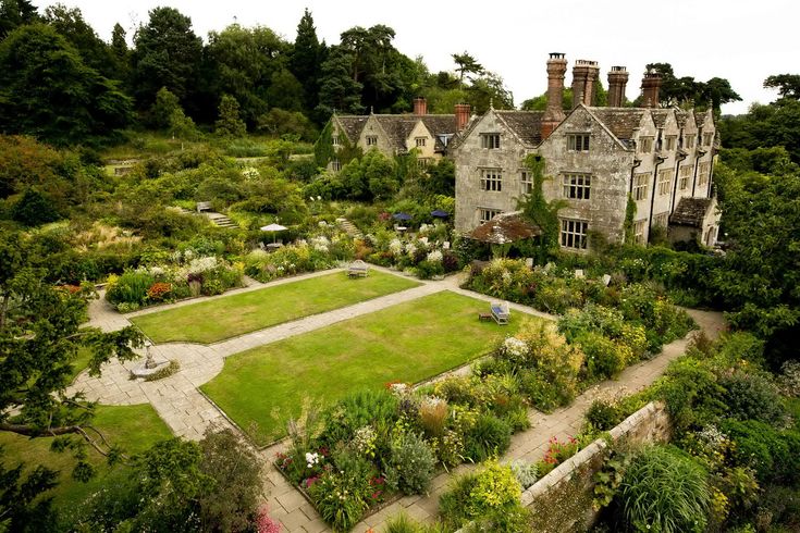 an aerial view of a large garden in front of a stone building with many windows