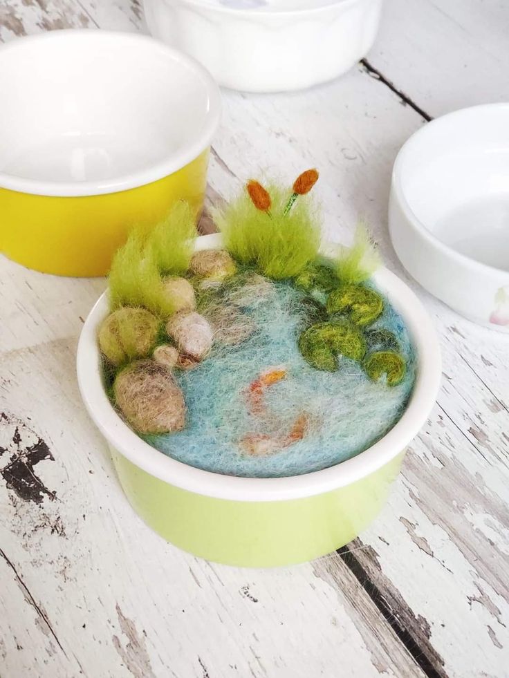 a bowl filled with water and rocks on top of a wooden table next to bowls