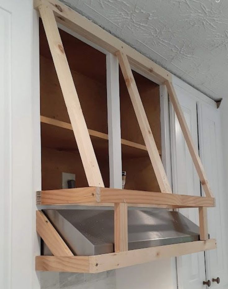 an unfinished kitchen cabinet with metal pans in it's upper shelf and bottom shelf