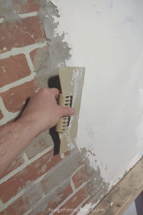 a person using a brush to paint a brick wall