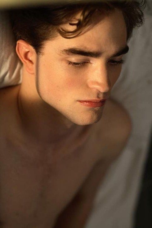 a young man laying in bed with his eyes closed and head turned to the side