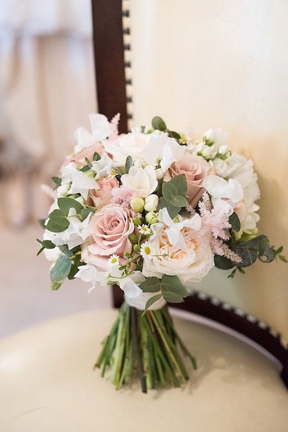 a bridal bouquet sitting on top of a chair next to a wall and window