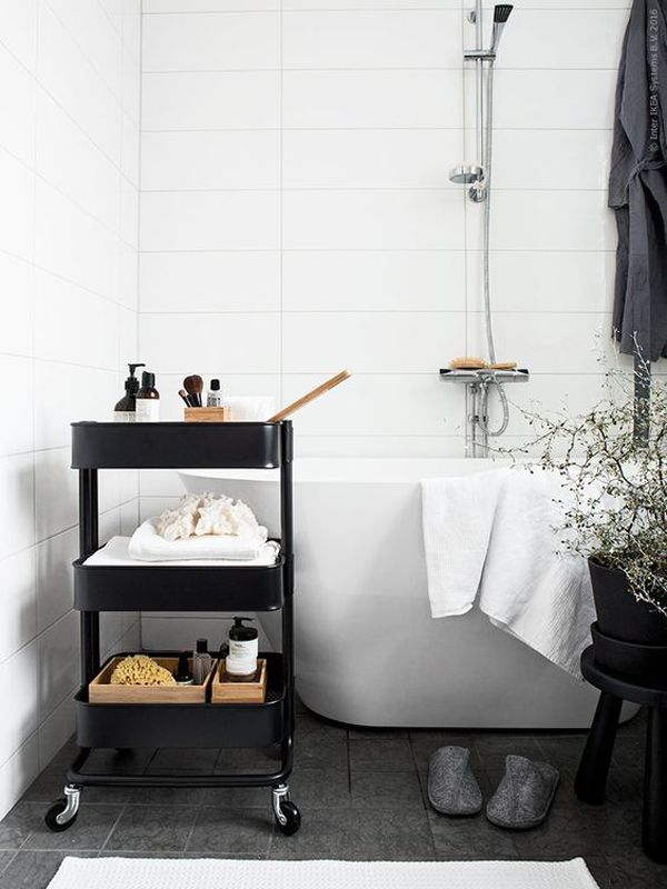 a black and white bathroom with a bathtub, shower head and shelves on the wall