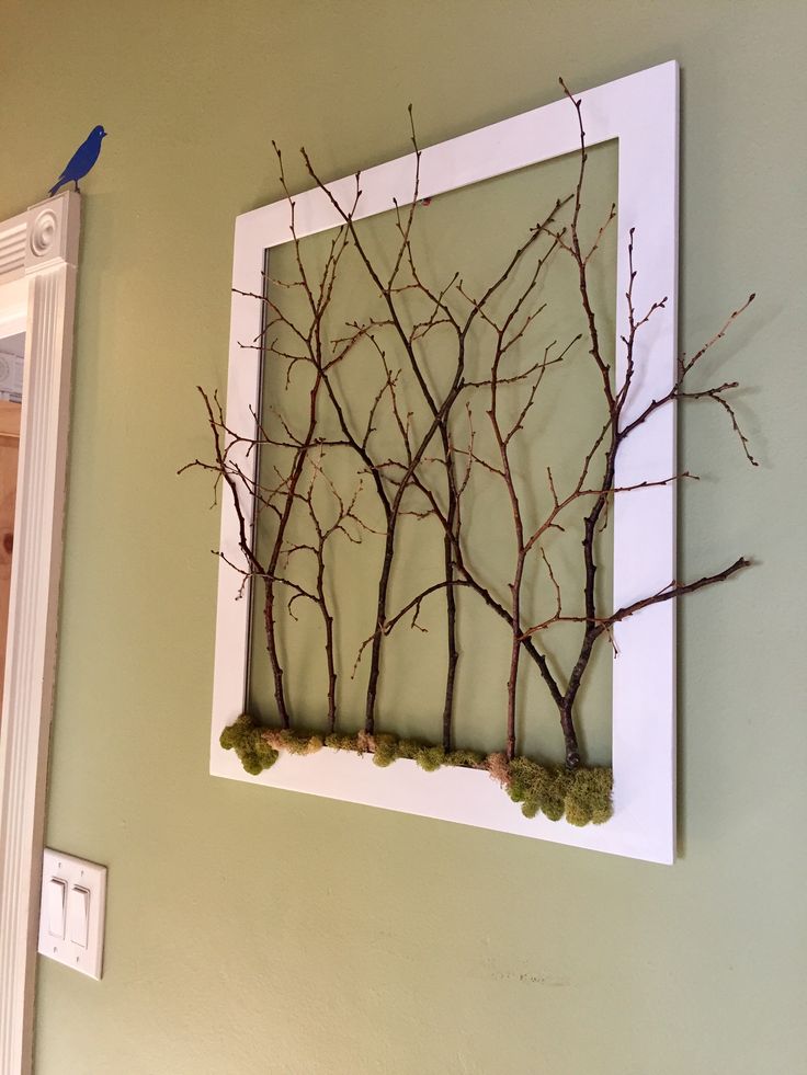 there is a picture frame with branches on the wall next to a mirror that has moss growing in it