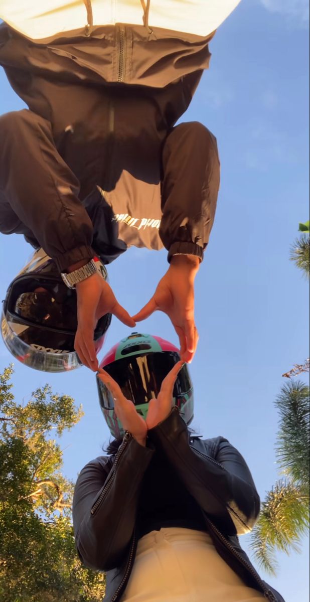 two people making a heart shape with their hands while standing on top of each other