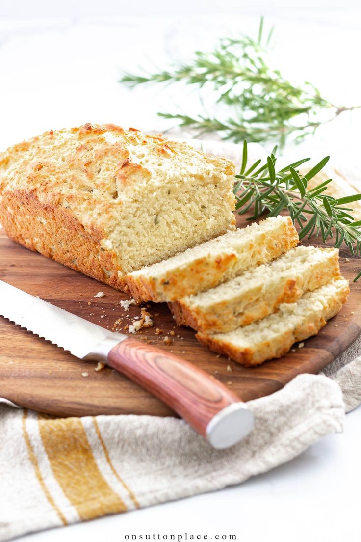 sliced loaf of bread sitting on top of a wooden cutting board next to a knife