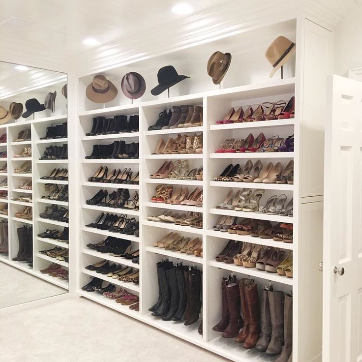 a white closet filled with lots of shoes and hats