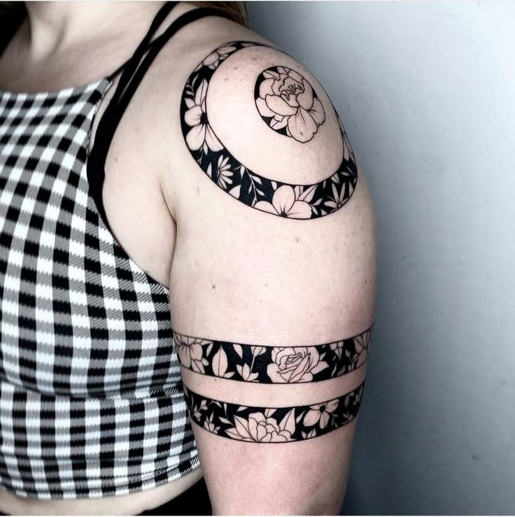 a woman wearing a black and white top with flowers on her arm