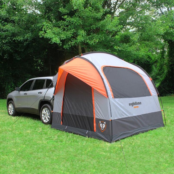 a car is parked next to a tent in the grass