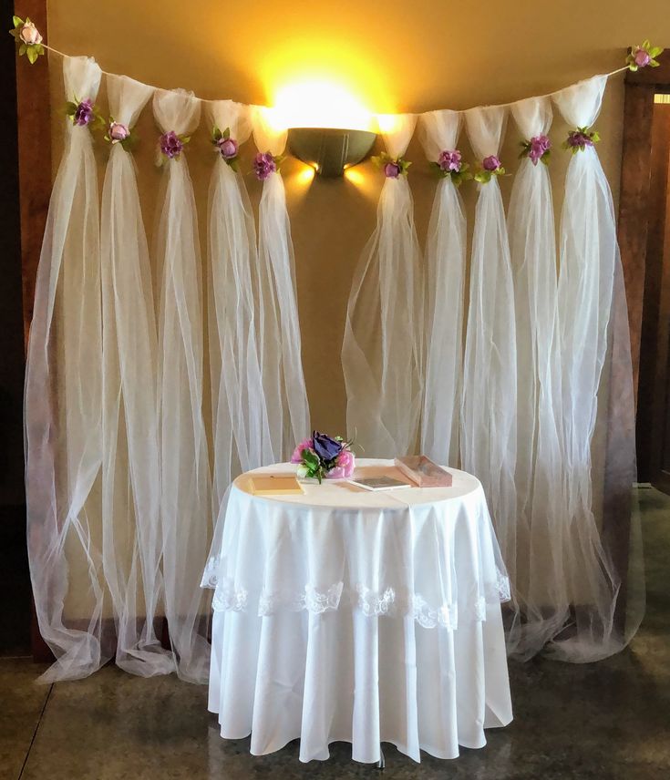 a table with a white cloth draped over it and some flowers on top of it