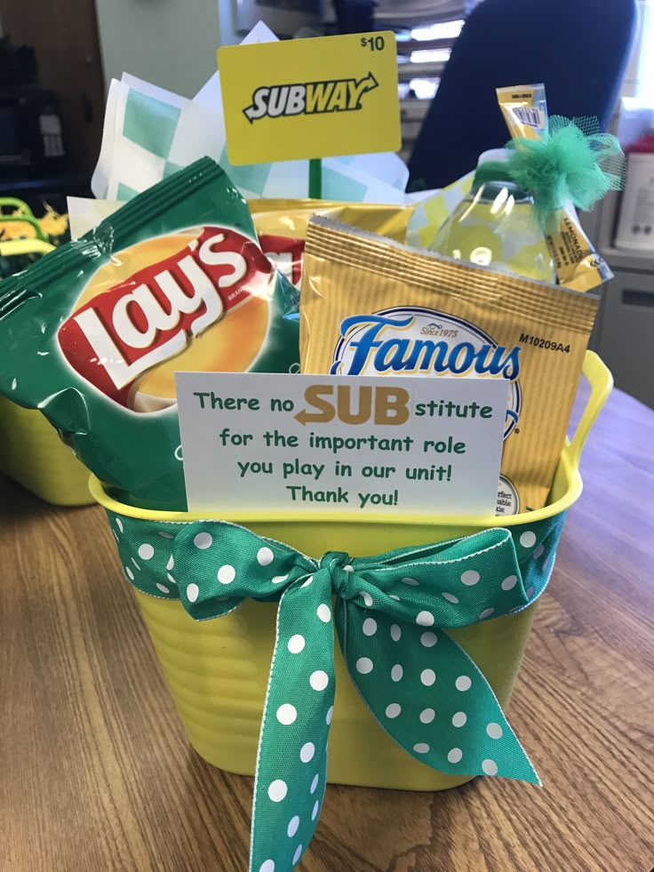 a yellow bucket filled with lots of different types of snacks and candy bars on top of a wooden table