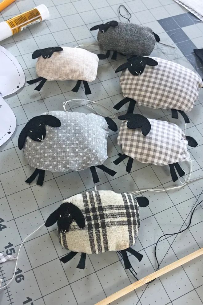 several sheep made out of fabric sitting on top of a table next to scissors and thread