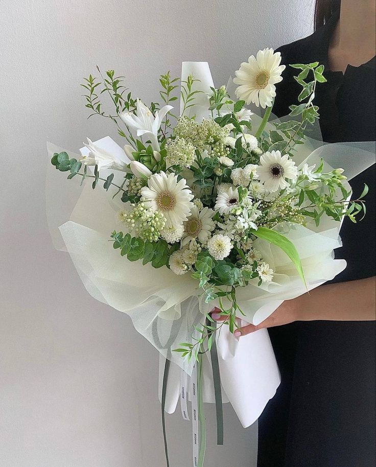 a woman holding a bouquet of white flowers