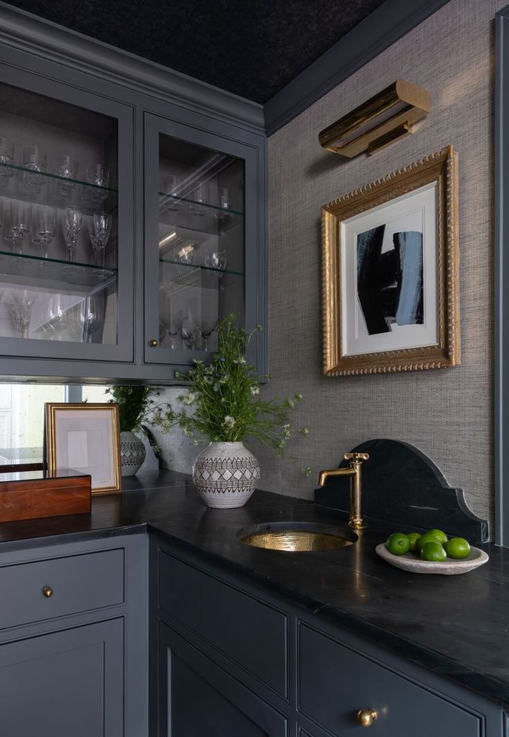 a kitchen with gray cabinets and black counter tops, gold trim on the cabinet doors