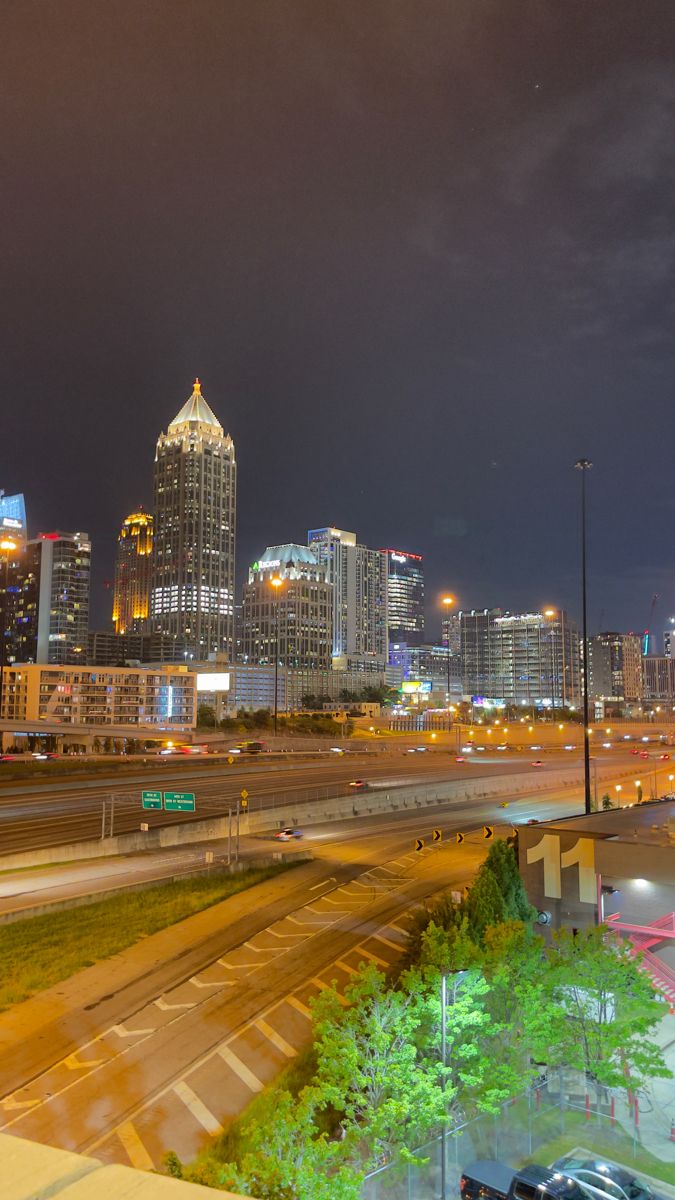 the city skyline is lit up at night, with cars driving on the road below