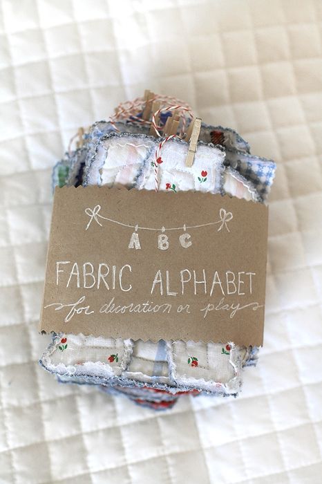 fabric alphabets are displayed on top of each other in small packages with a tag hanging from them