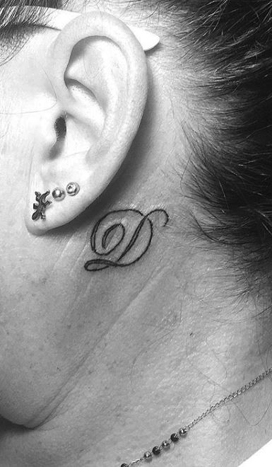 a woman with a tattoo on her neck and behind the ear is a small letter