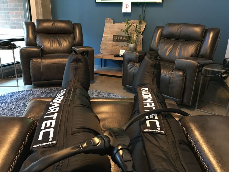 two recliners and a chair in a room with blue walls, one has a black leather cover on it