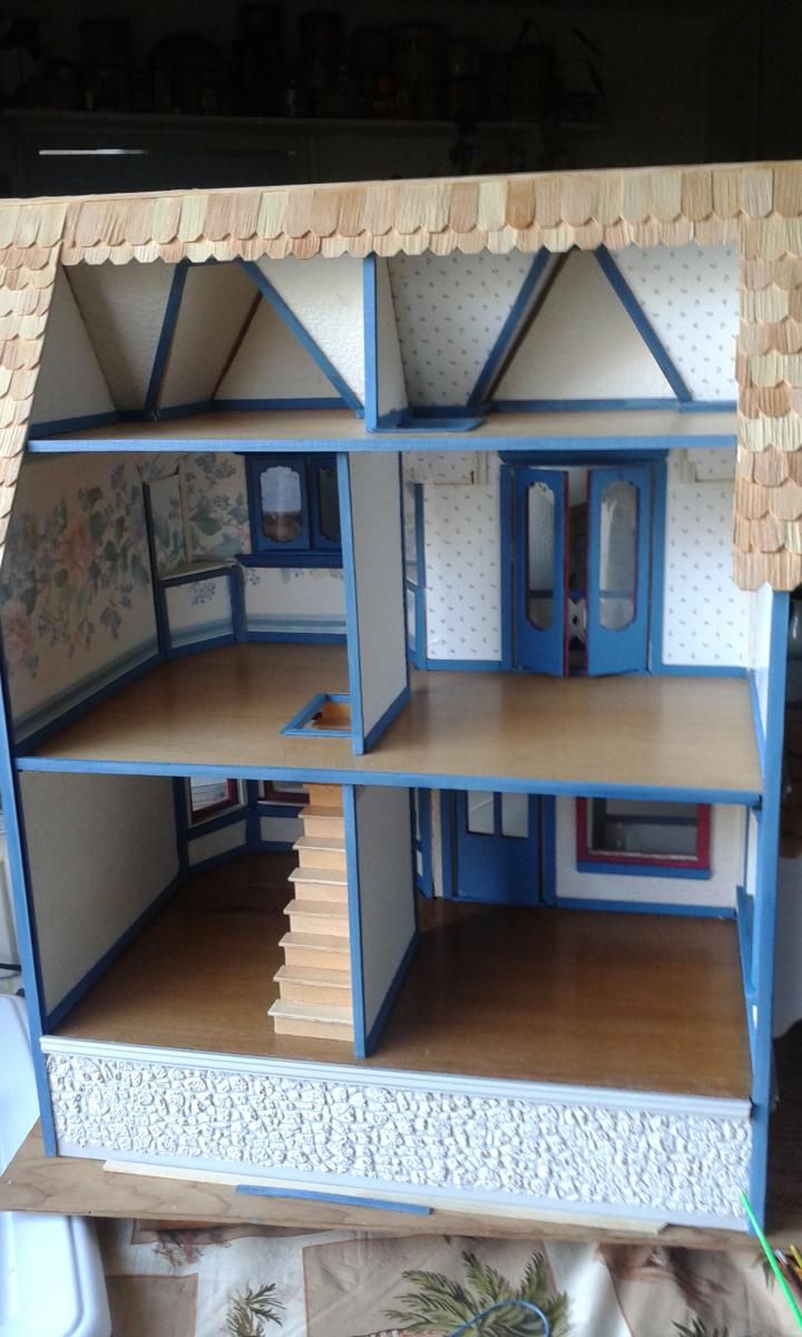 a doll house with blue trim and wooden floors