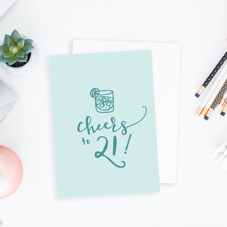 a card with the words cheers to 21 on it next to some pens and pencils