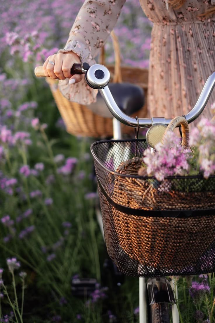 a woman riding a bike with a basket full of flowers