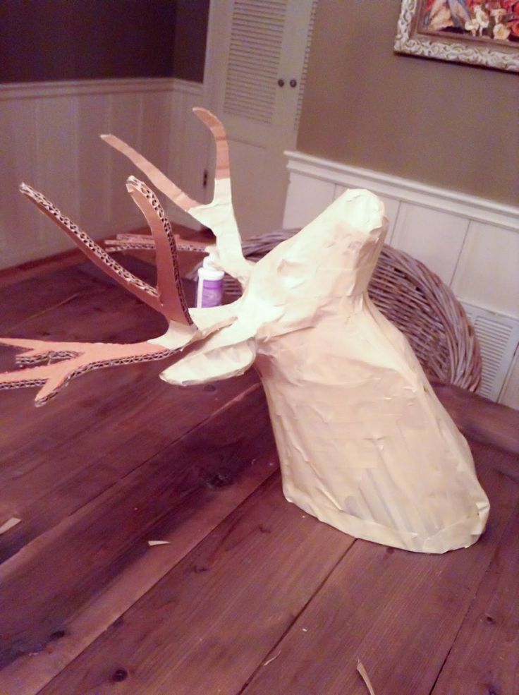 a deer head made out of paper sitting on top of a wooden floor