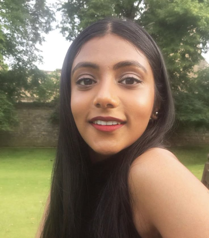 a close up of a person with long black hair and brown eyes wearing an earring