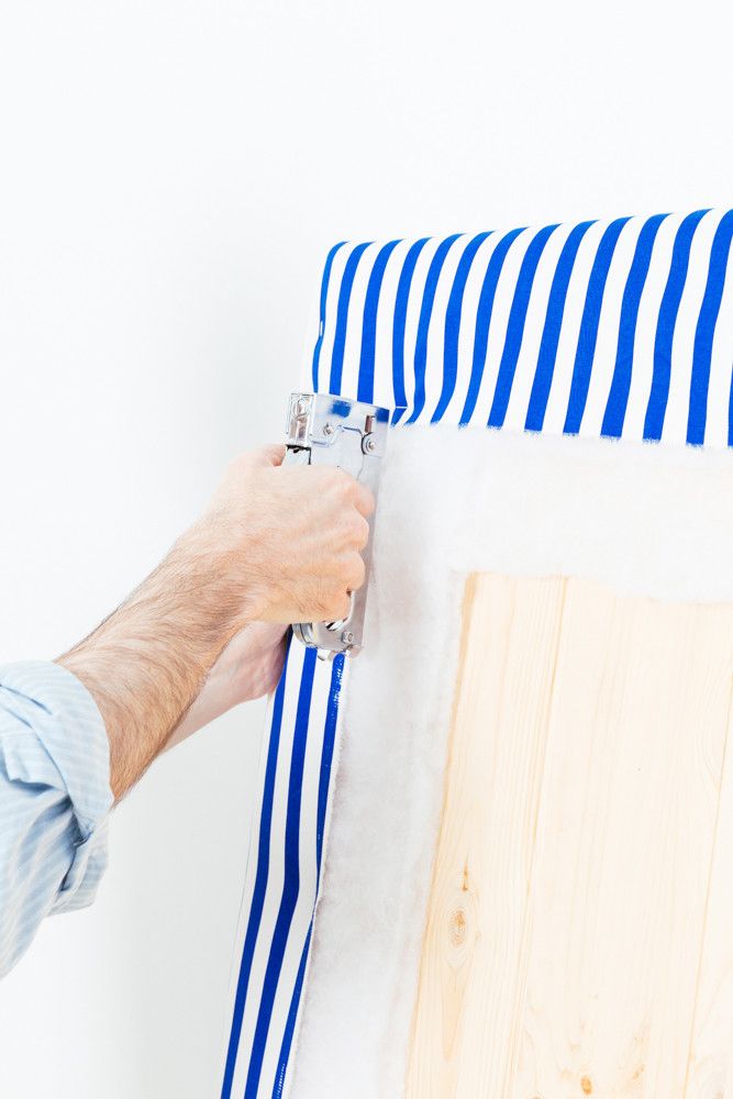 a person holding a pair of scissors near a piece of wood that has been painted blue and white