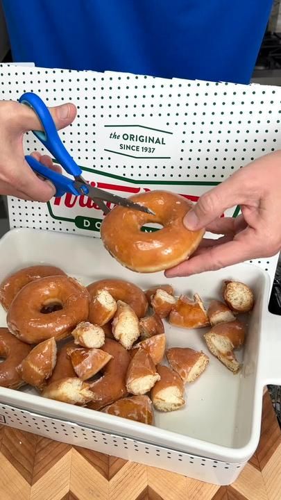 a person holding a doughnut in front of a box of donuts