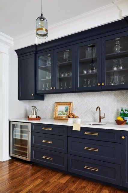 a kitchen with dark blue cabinets and gold pulls