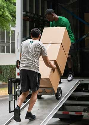 two men unloading boxes from the back of a moving truck