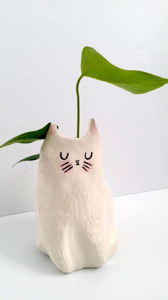 a white ceramic cat planter with a green leaf