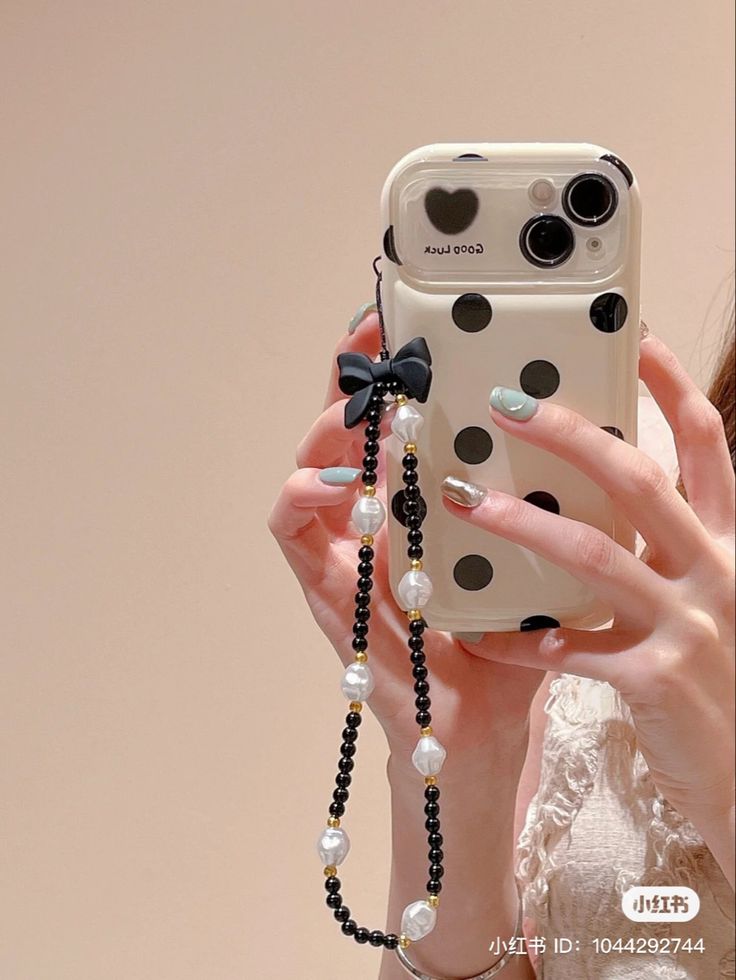 a woman taking a selfie with her cell phone wearing a polka dot case and beaded necklace