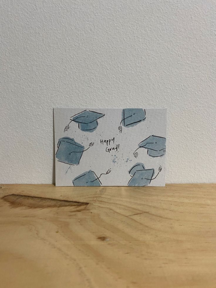 a card with graduation caps on it sitting on top of a wooden table next to a white wall