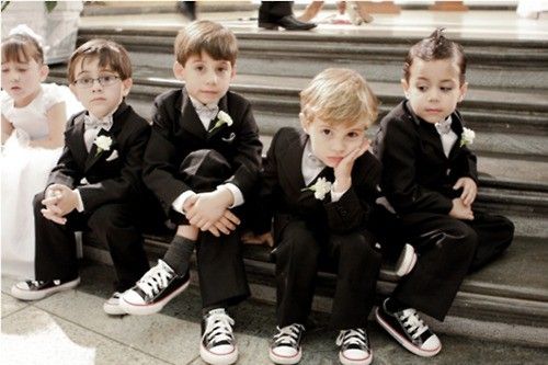 a group of young children sitting on top of steps wearing black suits and white shirts