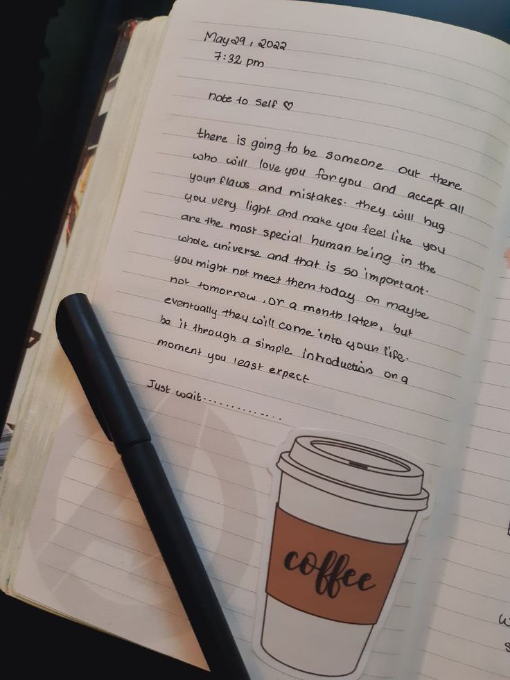 a coffee cup sitting on top of an open notebook