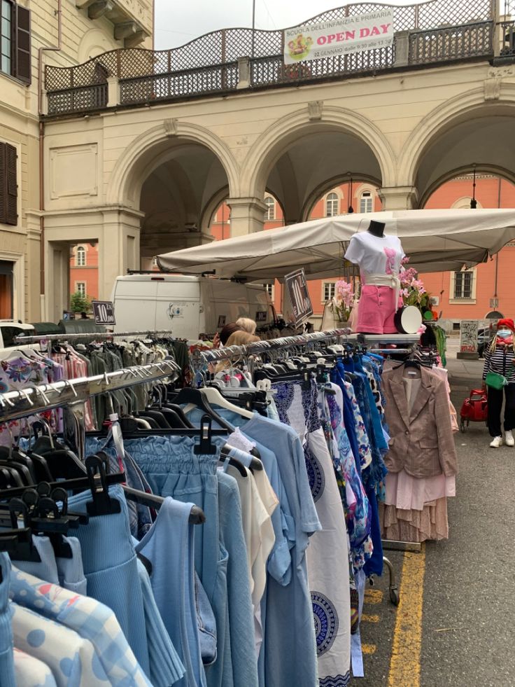 an outdoor market with clothes and umbrellas for sale